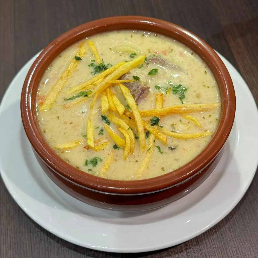 Peanut soup (sopa de maní) in a clay bowl, topped with fried potato strips and parsley