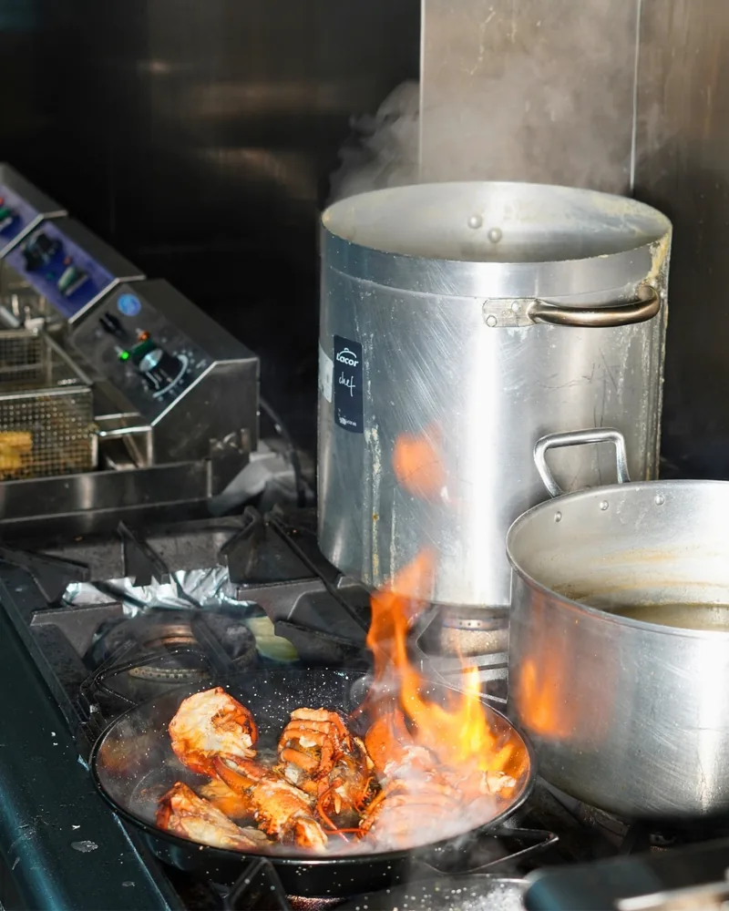 En la cocina, el marisco flambeado en la sartén, con la llama
