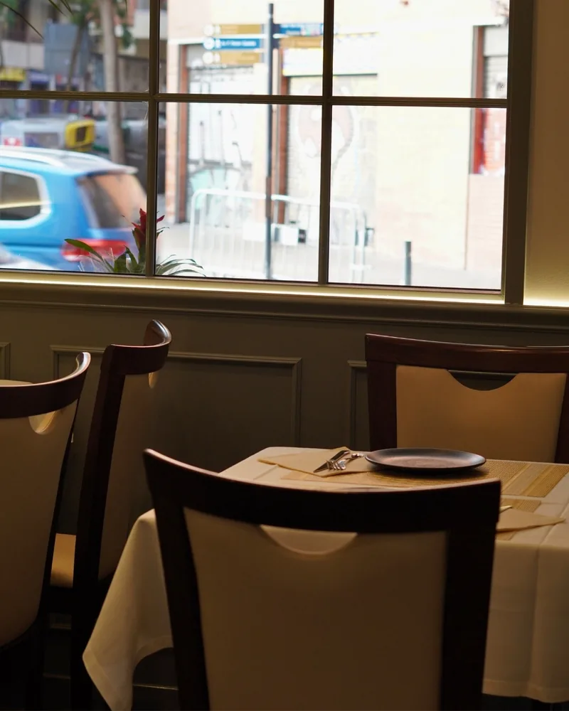 Una mesa del comedor junto a la ventana que da a la calle