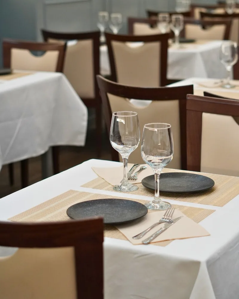 Mesas puestas en el comedor, con mantel blanco y copas