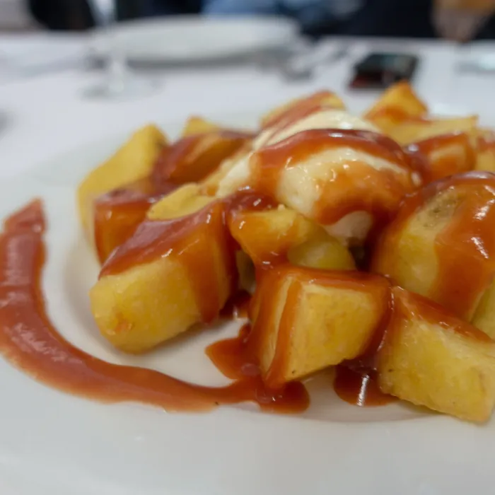 Patatas bravas con su salsa, en un plato blanco