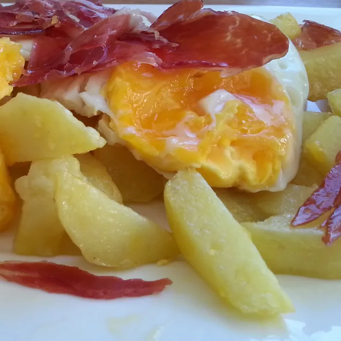 Huevos rotos con patatas y lonchas de jamón