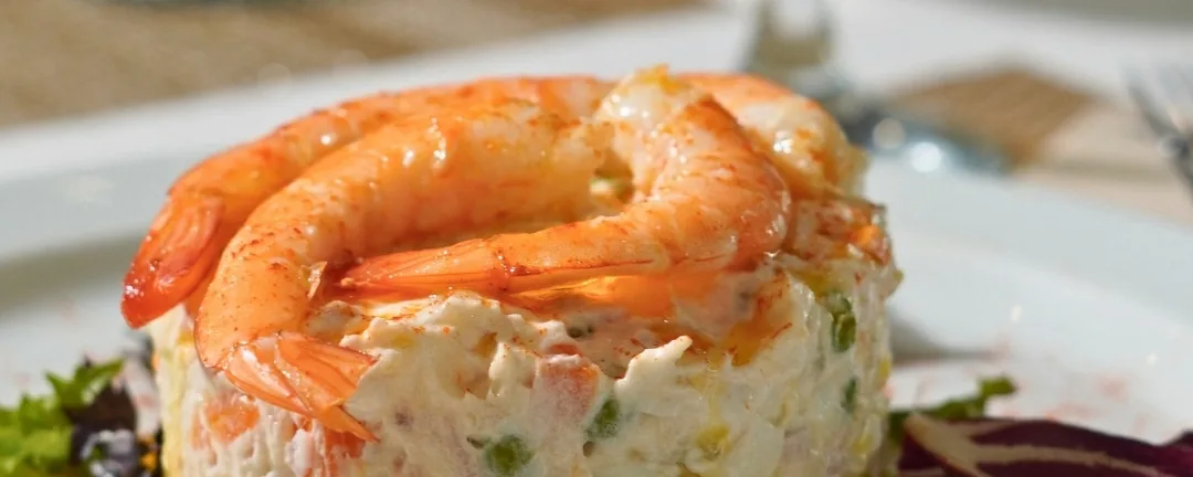 Una ensaladilla rusa coronada con langostinos, de cerca
