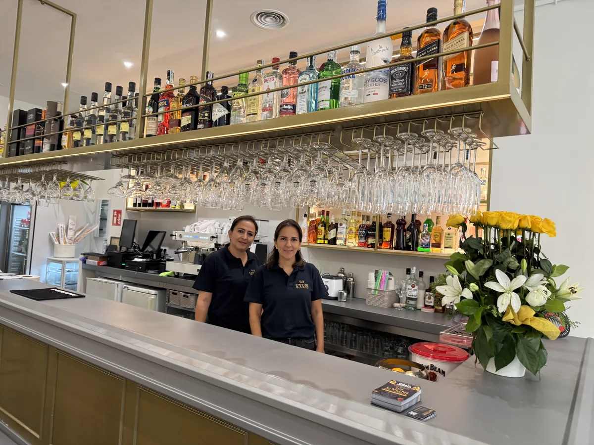 La barra de UYUNI, con dos personas del equipo y las botellas en la estantería