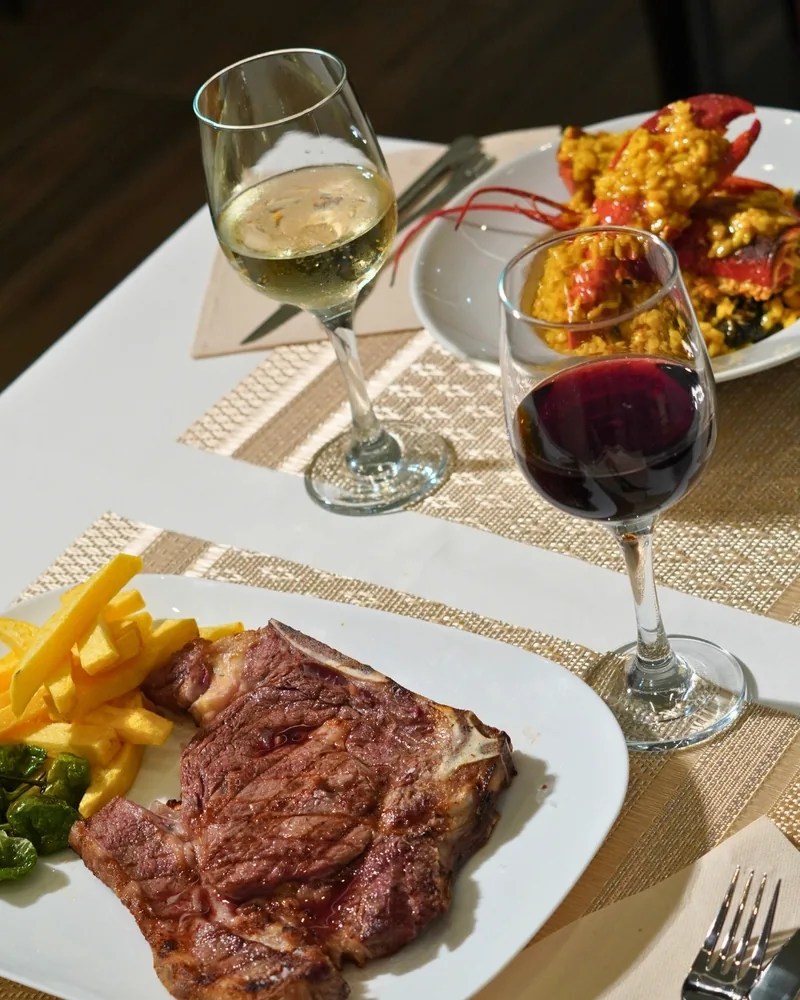 Un entrecot con patatas fritas, una copa de tinto y otra de blanco